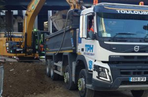 excavator loading dirt onto skip in truck